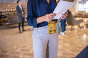 An unrecognizable mid adult woman holding a document and wearing a business ID card in a luxury hotel's lobby before a business conference starts